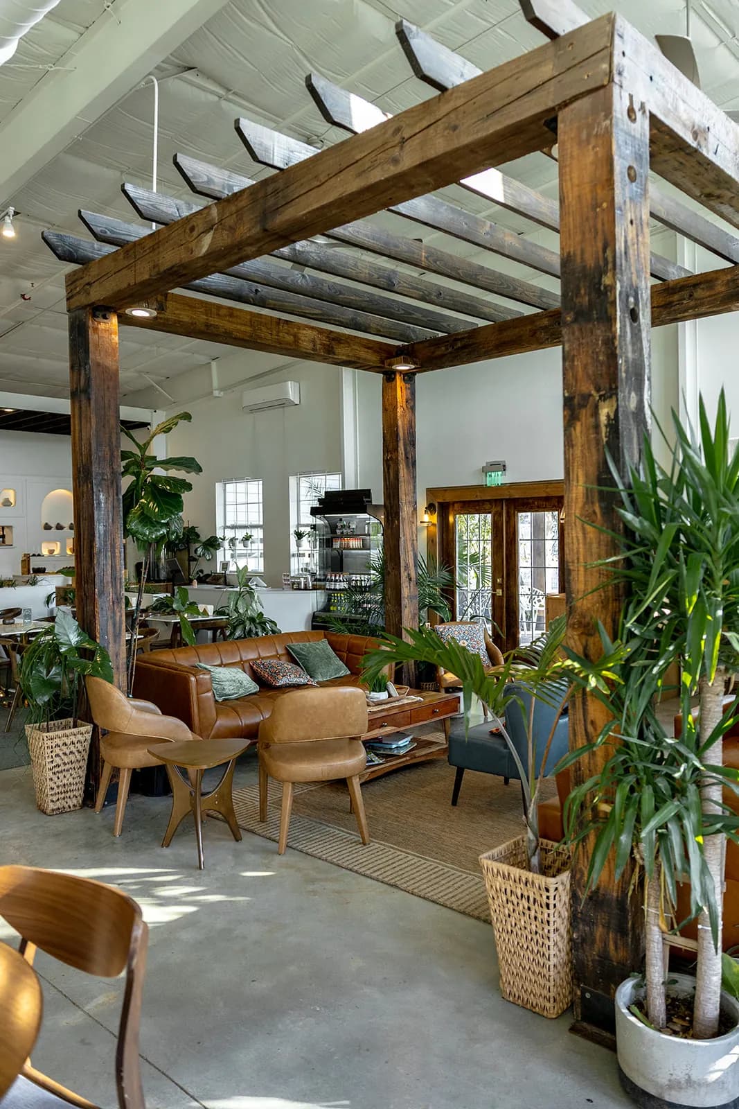 Manna Bakery lounge under a reclaimed timber pergola with cognac leather seating